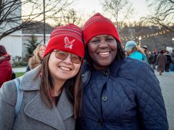 Two women smiling for camera wearing Montclair State University beanies