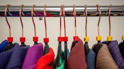 close-up view of a rack with color-coded hangers and colorful suit jackets