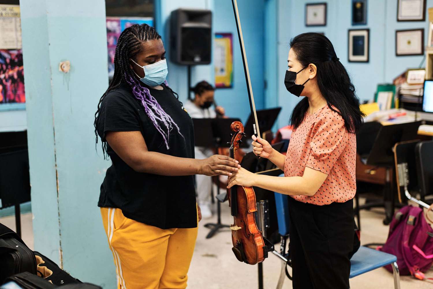 Two women hold a violin.