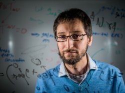 A man looks through a glass plate covered with physics equations.