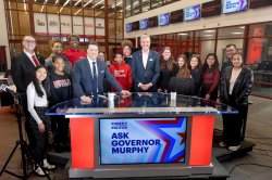 A group photo of students, a news anchor and the governor.
