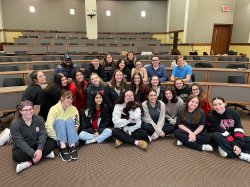 A large group of students smile and one holds a puppy.