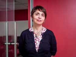 Professor Anna Feldman stands against a red wall.