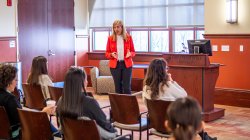 Valeria Aloe in a red blazer, speaking to a seated audience.