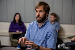 A male professor speaks as students listen.