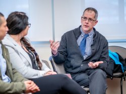 Male professor talks with two students.