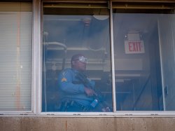 Police officer with assault rifle seen through window in Webster Hall