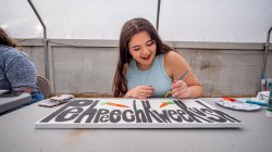 Female student paints sign.
