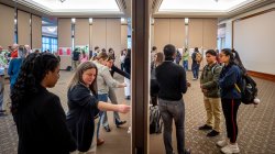 Many of the nearly 200 student researchers are shown explaining their research posters.