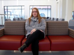 A smiling woman sits on a couch