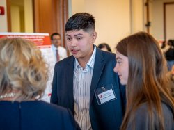 A student talks to two attendees about his research.