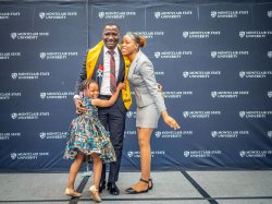 A small child and a young woman hug a male nursing student on the stage.