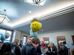 A happy face balloon with a nurse’s cap floats about a crowd of people.