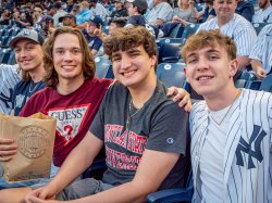 Four young men in the stands smile.