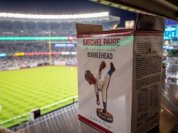 A box with a Satchel Paige bobblehead with a baseball field in the background.