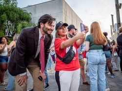 President Koppell and a woman smile as she takes a selfie with her phone.