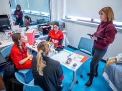 A nursing professor talks with three nursing students at a table