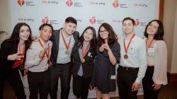 Seven students smile and gesture at the camera.