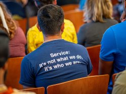 The back of a man’s shirt reads: “Service: It’s not what we do, it’s who we are.”