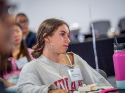 A student listens to a speaker at a dinner.
