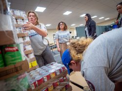 Students unload cans of food at a food pantry.