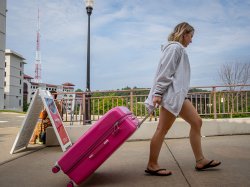 A student pulls a large hot-pink suitcase.