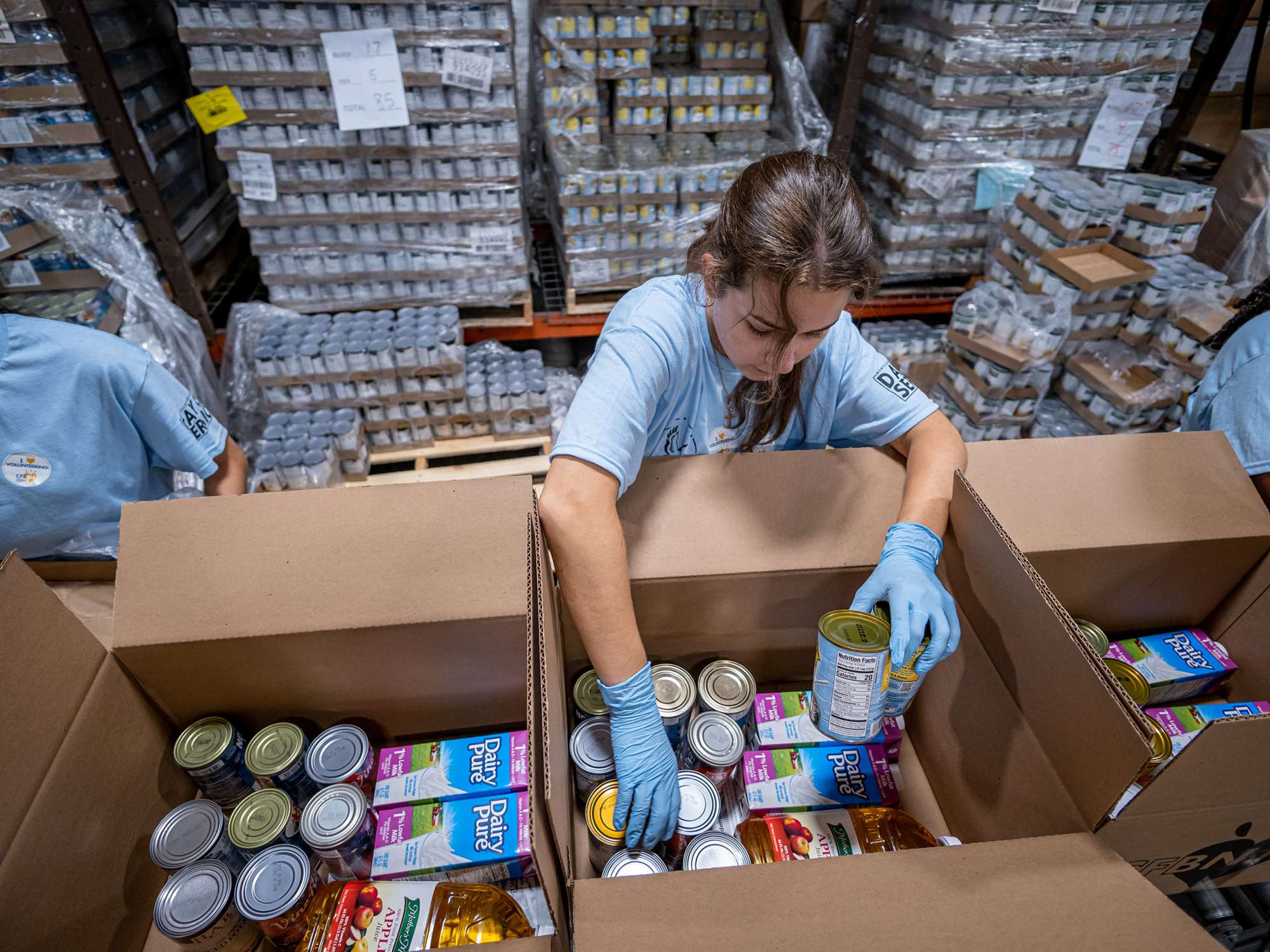A student packs a box with canned goods.