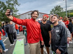 President Koppell holds a camera at arm's length to take a "selfie" with students.