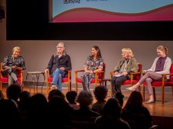 A panel of five women on stage.