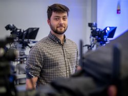 A student stands among TV cameras at Montclair’s News Lab.