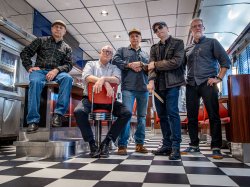 Five men stand in a diner with black and white checkered floor.