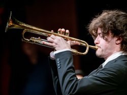 A young man plays a trumpet.