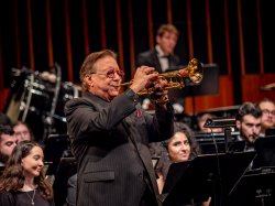 Arturo Sandoval plays the trumpet with students in the University Wind Symphony seated behind him.