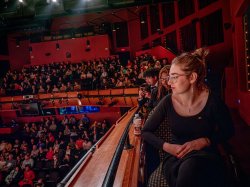 Audience members in a packed theater enjoy a concert.