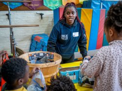 A student wearing an MLK Day of Service sweatshirt talks with some children.