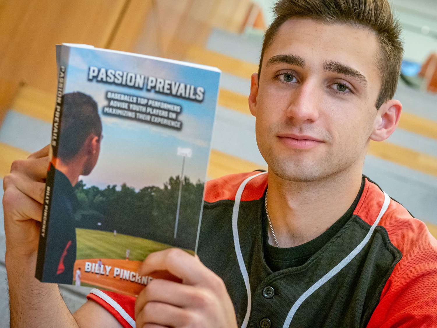 Billy Pinckney rests on his back on his baseball jacket and holds his book.