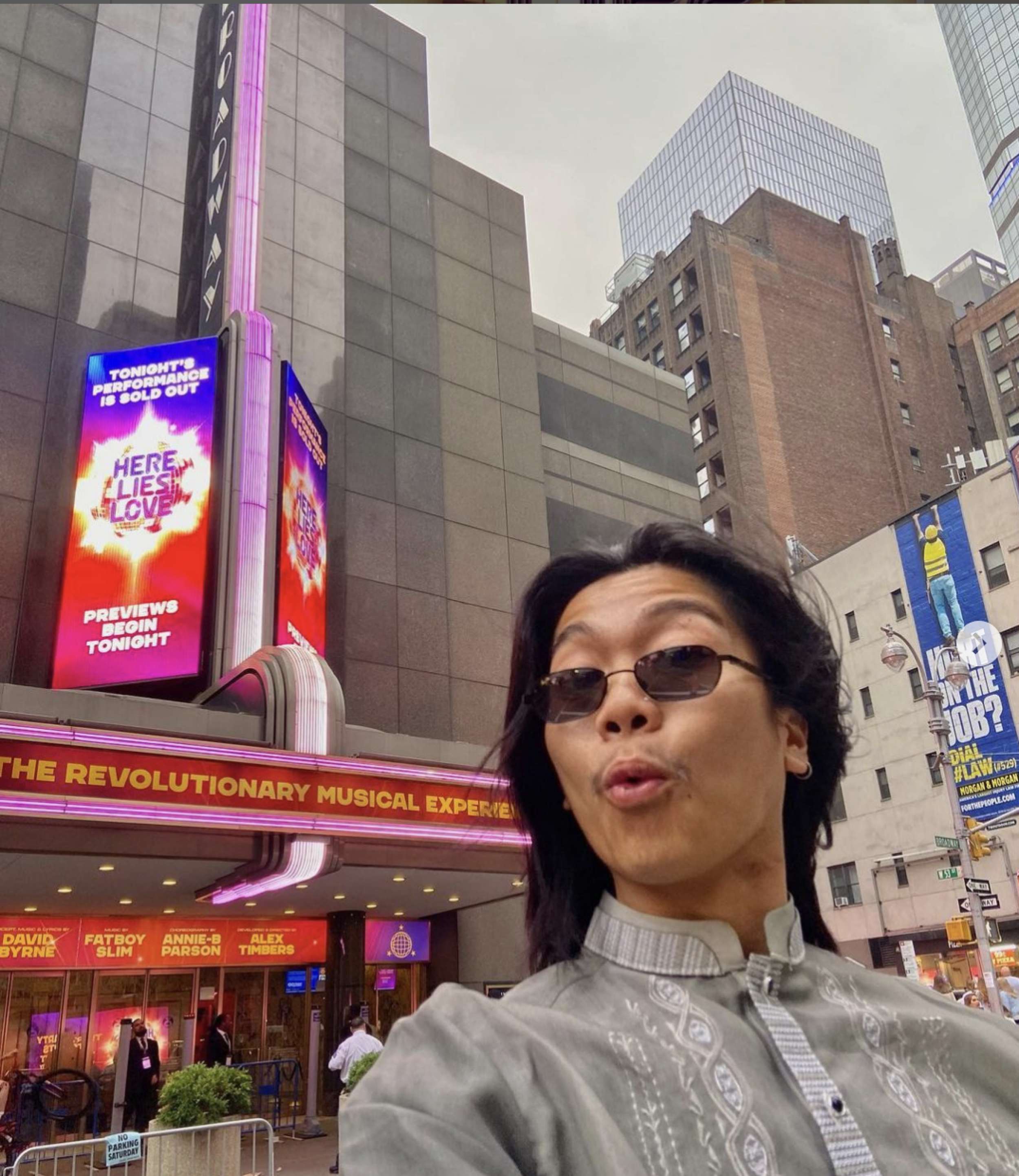 A young man in sunglasses in front of a Broadway theater.