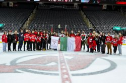 Montclair students and faculty stand on the ice with the New Jersey Devils logo.