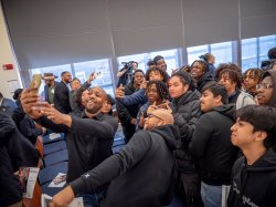 A group of adults and students take a group selfie.