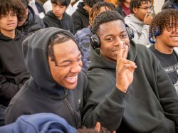 Two male students share a laugh, while one makes a peace sign.