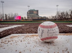 An autographed baseball with the field in the background.