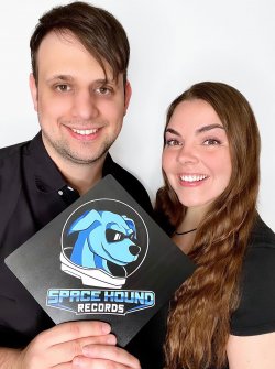 Corey Morgart and Therese Sheridan hold a sign that says Space Hound Records with a logo of a dog wearing a space helmet.