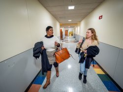 Two students walk down a hallway.