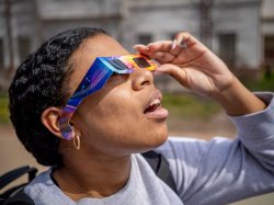 A student looks up wearing solar safety glasses.