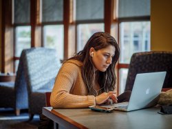 Woman working on a laptop wearing headphones