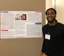 A man smiles in front of his research poster.