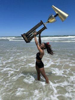 A cheerleader hoists a large trophy over her head at Daytona Beach.