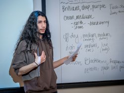 Godek presents in front of a white board in class about the qualities of the wine.