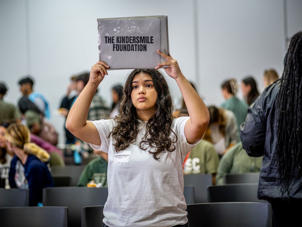 Samantha Almonte holds a sign for the KinderSmile Foundation to help guide volunteers at a Day of Service event.