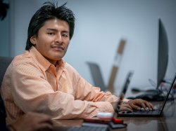 Mateo Llano is typing on a laptop on a presentation for Hispanic Heritage Month.